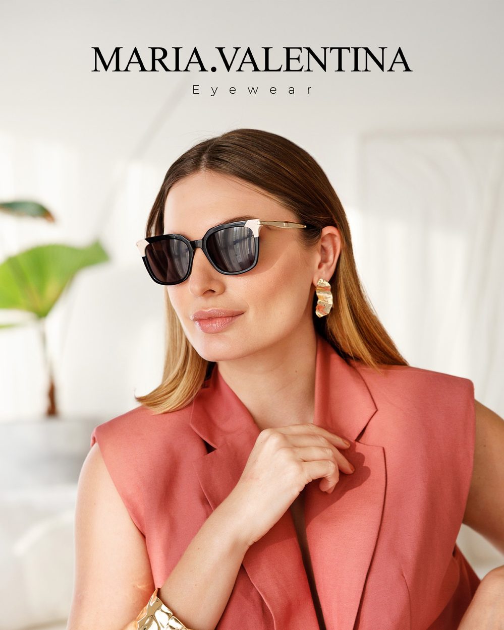 Mulher de blazer coral usando óculos de sol Maria Valentina